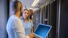 Worker with laptop talking to other IT workers Worker with laptop talking to other IT workers