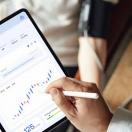 Healthcare worker looking at medical record on tablet with patient in background