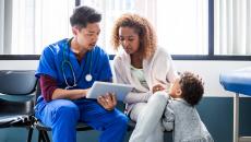 Healthcare worker showing tablet to patient and child