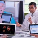 Doctors meeting with laptops and other doctor on a screen Doctors meeting with laptops and other doctor on a screen
