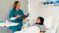 Doctor with clipboard talking to patient in hospital bed Doctor with clipboard talking to patient in hospital bed