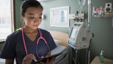 Nurse checks tablet to communicate on shift Nurse checks tablet to communicate on shift