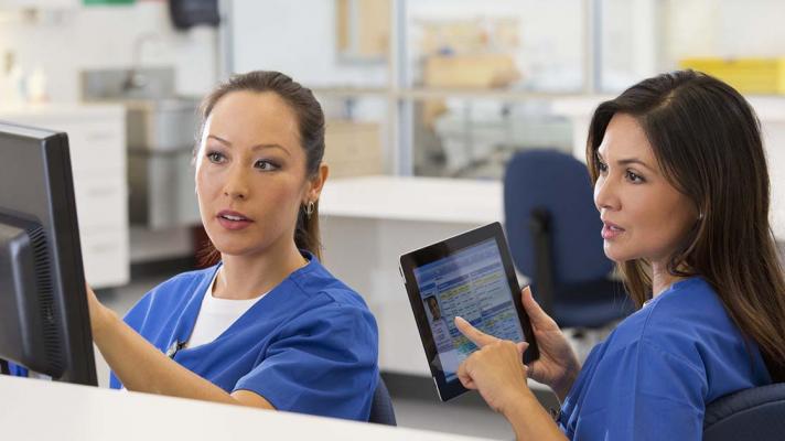 Two nurses confer about clinical documentation