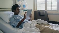 Patient using tablet in bed.