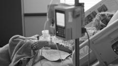 Woman asleep in hospital bed with IV in foreground