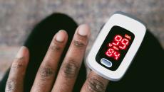 Dark skinned hand with a pulse oximeter measuring the patient's oxygen levels