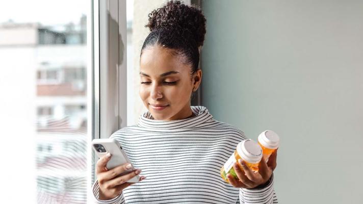 Smartphone user holding a pill bottle