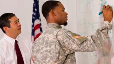 veteran draws on a whiteboard with a colleague