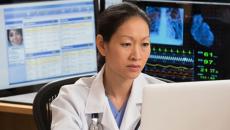 female doctor reviews patient data on multiple screens