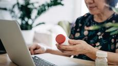 Patient checks pill bottle against her patient record on a laptop