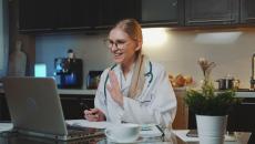 A doctor taking a virtual consultation from their kitchen and dining room A doctor taking a virtual consultation from their kitchen and dining room
